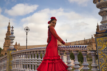Portrait of young teenage woman in red dance suit with ruffles and red carnations in her hair doing...