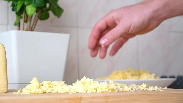 A man rubs cheese on a metal grater for freezing and further cooking pizza, pasta.