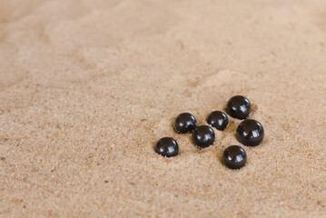 black round pearls on the sand