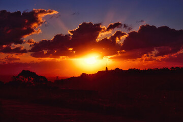 Dramatic sunset scene over hills in the countryside with deep shades of orange, red and blue
