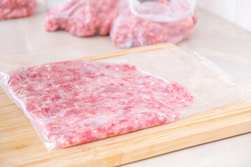 A man makes flat minced pork and beef in bags for storage in the freezer.