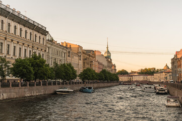 Obraz premium View of the Moika River and a string of pleasure boats with tourists. City landscape of St. Petersburg.Golden hour. White Nights.