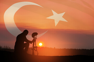 Silhouette of soldier kneeling with his head bowed against the sunrise or sunset and Turkey flag. Concept of crisis of war and conflicts. Greeting card for Turkish Armed Forces Day, Victory Day.