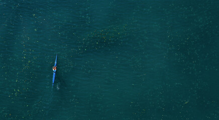 Drone view of sport kayak on the lake operated young sports man. Aerial lake with blue water and...