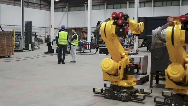 Industrial workers working inside automation and robotics facility - New industry technology concept