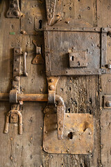 Old vintage lock on a weathered wooden door with diffused sunlight.