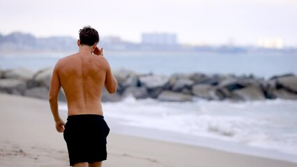 Athletic man jogging at the beach in Southern California. Slow Motion.