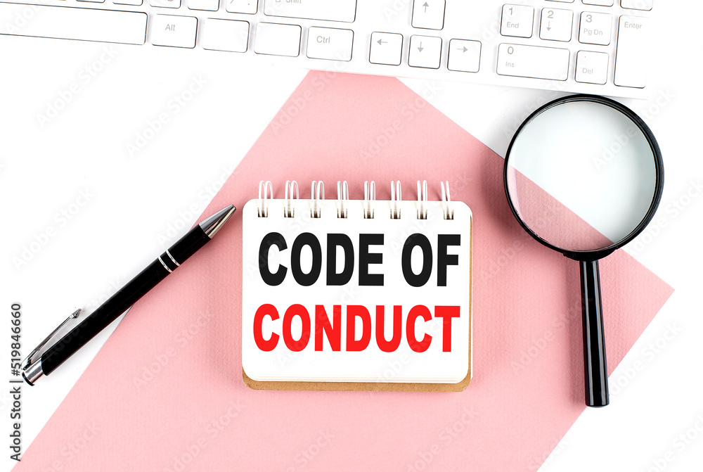 Poster business concept. notebook with text code of conduct on pink paper with magnifier, keyboard and pen 