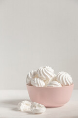 small white meringue in a deep pink plate on a white background