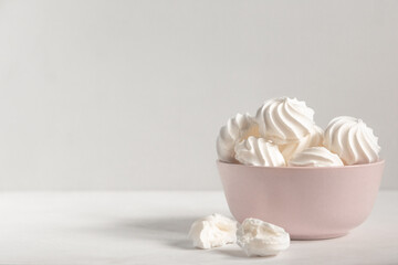 Fototapeta na wymiar small white meringue in a deep pink plate on a white background