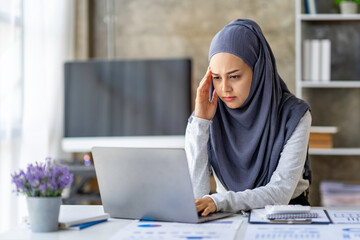 Muslim businesswoman wearing hijab tired sleepy and bored from sitting at a desk for a long time have trouble and problem of her work. and has office syndrome