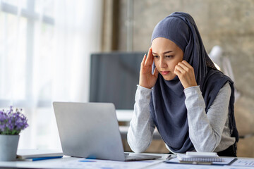 Muslim businesswoman wearing hijab tired sleepy and bored from sitting at a desk for a long time...