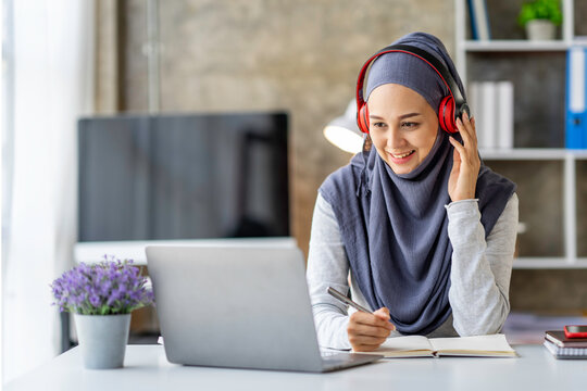 Muslim businesswoman wearing a hijab looks at camera working Online Tutoring. Young Muslim woman teacher having a video call with students
