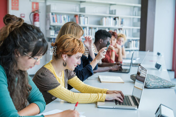 Group of college students studying together in the library