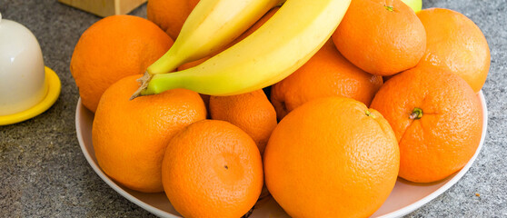 On the table are bananas and oranges in a plate