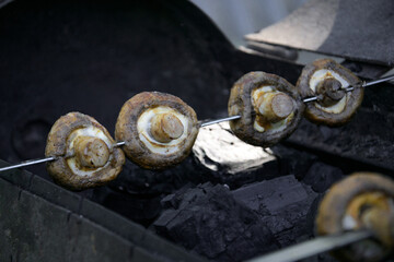 White mushrooms champignons are planted on skewers lie on the grill
