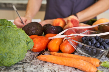vegetables and fruits while an unrecognizable female nutritionist writes a balanced diet
