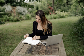 Obraz premium Geschäftsfrau arbeitet in freier natur auf einem Laptop am Holztisch