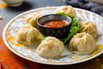 Indian food Momo with meat and tomato sauce on dark blue table macro close up