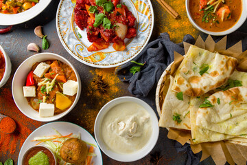 chicken tikka masala, kadai chicken; coconut sabdji, indias samosa, veg curry;bainkar bharta,  Indian food on dark blue stone background with spices top view