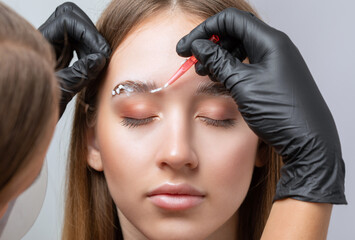 The make-up artist does Long-lasting styling of the eyebrows of the eyebrows and will color the...