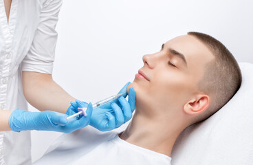 Men's cosmetology. Beautician makes a man a rejuvenation injection procedure of a handsome young man in a beauty salon. Professional make-up and face care.