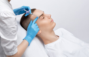 Obraz premium Men's cosmetology. Beautician makes a man a rejuvenation injection procedure of a handsome young man in a beauty salon.