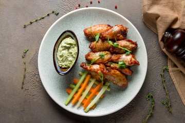 Buffalo chicken wings with sauce on plate on brown table top view