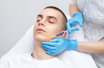 Men's cosmetology. Beautician makes a man a rejuvenation injection procedure of a handsome young...
