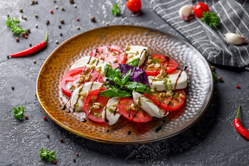 Caprese salad with mozzarella and tomato with basil and cream balsamic on brown plate