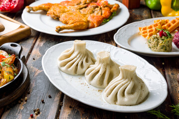 Khinkali with lamb on white plate, georgian cuisine on old wooden table