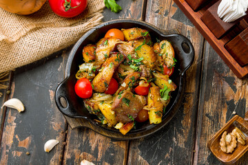 Ojakhuri georgian kitchen with pork, potatoes and vegetables on old wooden table