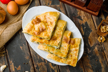 khachapuri with spinach and cheese sliced on white plate georgian cuisine on old wooden table top view