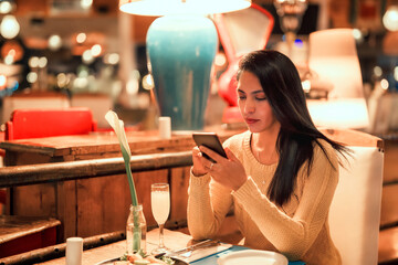 latin young woman sitting in cafe or restaurant using smartphone 