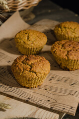 Biscuit cupcakes on paper on wooden background with hard light with selective focus