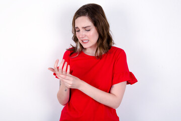 young caucasian woman wearing red T-shirt over white background Suffering pain on hands and...