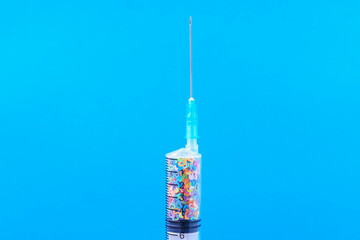 A disposable syringe filled with symbolic hearts. Love concept. Background with copy space. Blue...