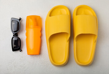 Flat lay composition with beach accessories on white texture background. Beach slippers,sunglasses and sunscreen.SPF sun protection.Space for copy.Place for text.Vacation concept.