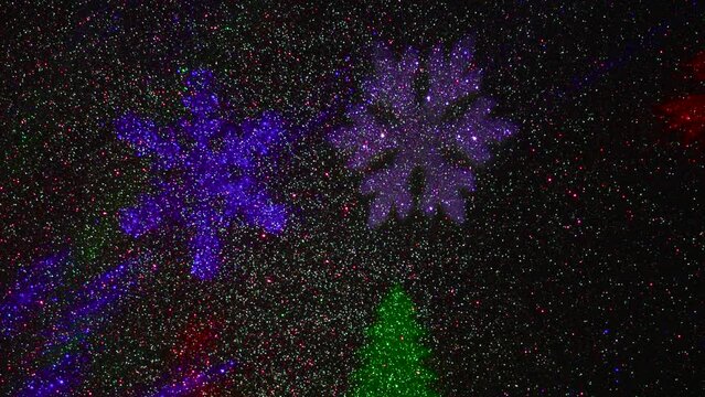 A carousel of light beams of different colors is set against a constantly flashing background that changes colors. Flying colored silhouettes of Christmas trees and snowflakes.