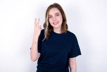 Obraz na płótnie Canvas young caucasian woman wearing black T-shirt over white background smiling and looking friendly, showing number two or second with hand forward, counting down
