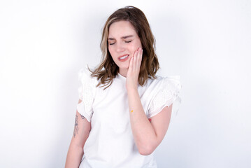 young caucasian woman wearing white T-shirt over white background with toothache