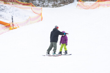 Ski Resort Father Teaching Little Daughter Snowboarding