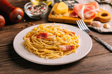 Classic italian pasta carbonara on white plate wooden tabletop, Close-up selective focus