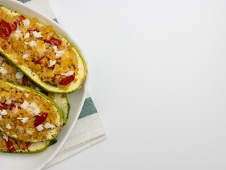 Grilled zucchini stuffed with couscous, tomatoes, cucumber and parsley. Vegan stuffed zucchini on a cutting board. Vegetarian food.