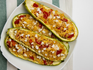 Grilled zucchini stuffed with couscous, tomatoes, cucumber and parsley. Vegan stuffed zucchini on a cutting board. Vegetarian food.