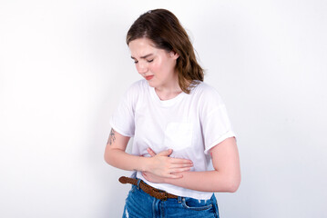 young caucasian woman wearing white T-shirt over white background suffering from strong stomachache.