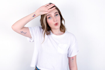 young caucasian woman wearing white T-shirt over white background wiping forehead with hand making...