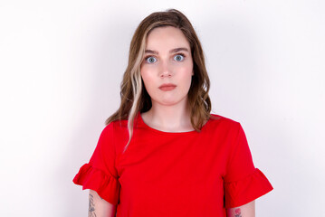 Stunned young caucasian woman wearing red T-shirt over white background stares reacts on shocking...