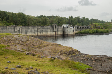 Fototapeta na wymiar The dam at loch Doon in Carrick Scotland. This structure was built to create a hydroelectric generator which raised the water level making dramatic outdoor scenery popular for walkers and fishing