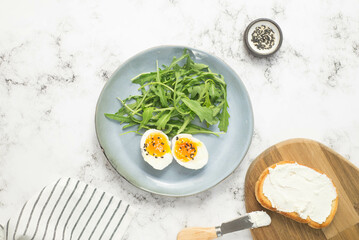 boiled eggs with arugula on a gray plate on gray background.